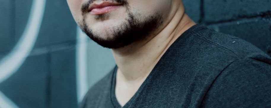 Retrato de un hombre con gorra negra sobre un fondo neutro.